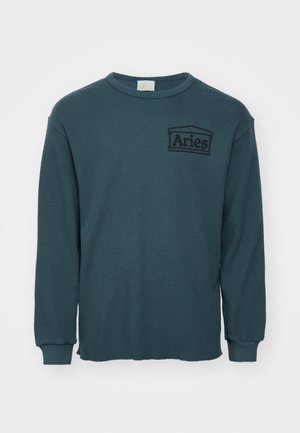 Tee-paita pitkissä hihoissa, valmistettu rakenteellisesta vohvelineuloksesta, turkoosinvärinen, jossa on pyöreä pääntie ja brodeerattu "Aries"-logo vasemmassa rinnassa.