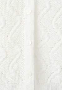 Tissu tricoté blanc avec des motifs en zigzag et en diamant, avec une rangée verticale de trois boutons blancs au centre.