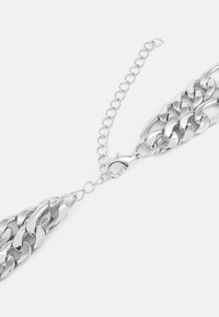 Bratara din metal argintiu cu link-uri mari, textură netedă și închidere cu carabină; include o lanț extensibil reglabil.
