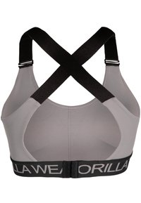 Sostenedor deportivo gris con tirantes entrecruzados negros y banda elástica con letras blancas. Textura suave y diseño minimalista.