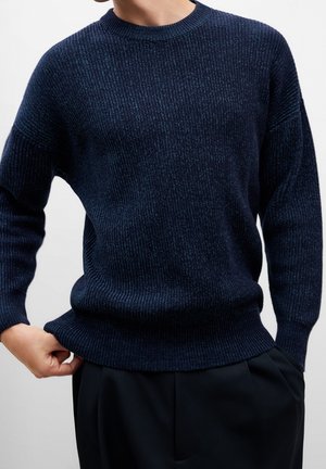 Pull en tricot côtelé bleu marine avec un col rond et des manches longues, offrant une coupe décontractée et un tissu texturé.