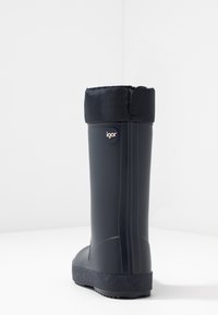 Botte de pluie en caoutchouc noire avec une semelle texturée, surmontée d'une manche en tissu. Présente un logo "igor" sur le côté. Design élégant et haut.