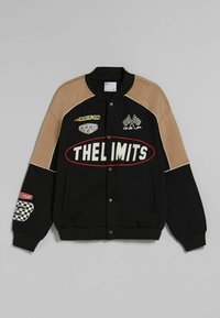 Černá a hnědá varsity bunda s závodními nášivkami, včetně "THE LIMITS", nalezených vlajek a sloganů na přední části a rukávech.