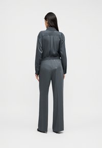 Γκρι σατέν πουκάμισο με πίσω γιακά και μακριά μανίκια, συνδυασμένο με ταιριαστό παντελόνι με ευρεία παντελόνα και ελαστική μέση.