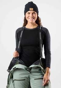 Black beanie, long-sleeve black top with gray accents, and green snow pants with front pockets. Straps labeled "SWEDMOUNT" visible.