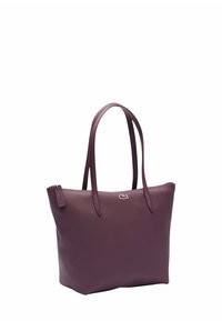 Bolso tote sintético púrpura con dos asas, cierre de cremallera y un pequeño logotipo en la parte frontal. Textura suave y forma estructurada.