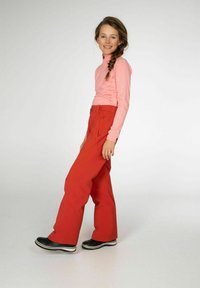 Rode wijde sneeuwbroek met een hoge tailleband, gecombineerd met een roze langemouwen top. Zwarte schoenen met witte accenten. Soepele stoffen.