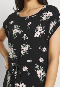 Robe noire à motifs floraux avec manches courtes, encolure ronde et taille à cordon de serrage. Le tissu présente des motifs floraux roses et verts.