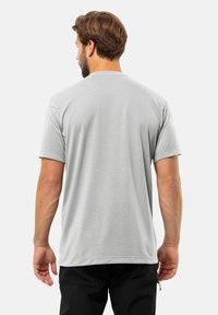 T-shirt grigio a maniche corte in un tessuto morbido e liscio. Presenta un collo a giro e maniche arrotolate, con una vestibilità rilassata.