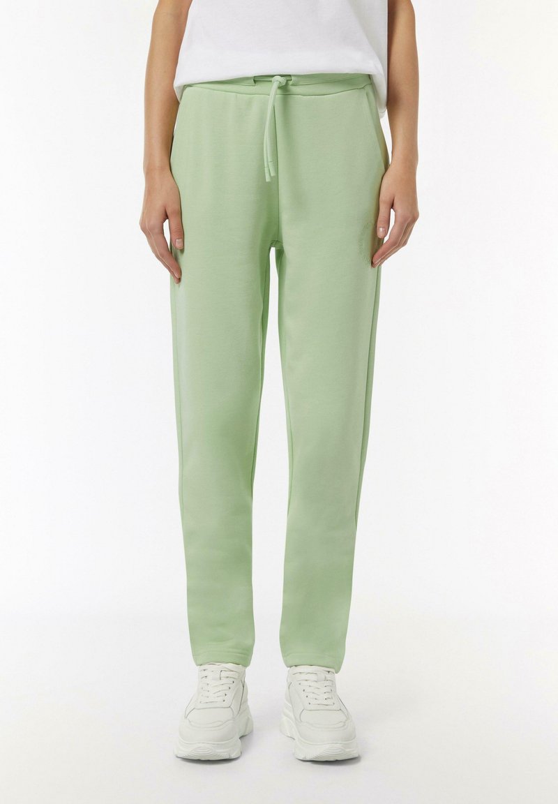 Hellgrüne Jogginghose aus weichem Stoff, mit einem elastischen Bund und Kordelzug, Seitentaschen und einer schmal zulaufenden Form.