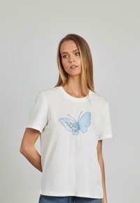 T-shirt bianca in cotone con un design ricamato a farfalla blu sul davanti. Maniche corte e colletto rotondo.