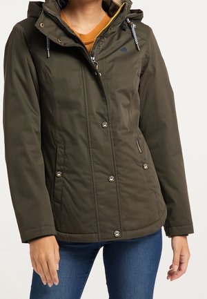 Olivgrüne Kapuzenjacke mit Reißverschluss und Druckknöpfen, getragen über einem senffarbenen Oberteil und blauen Jeans, dargestellt an einer Person von Hals bis Hüfte.