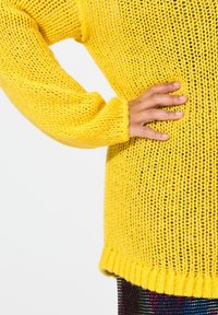Gelber gestrickter Pullover mit lockerer Passform, gerippten Bündchen und Saum. Verfügt über ein strukturiertes Muster mit sichtbaren offenen Stichen.