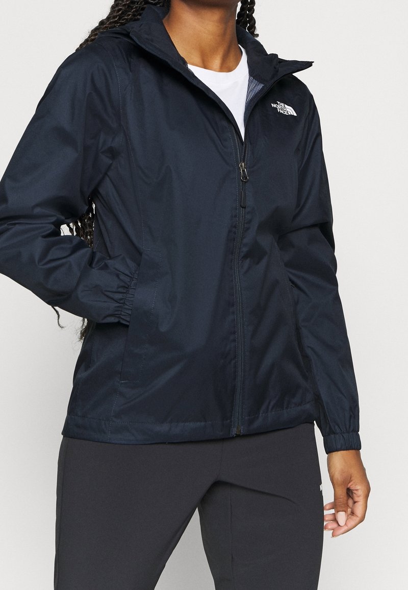 Laivastonsininen tuulta estävä takki, jossa on vetoketjulla varustettu etuosa, joustavat hihansuut ja huppu. Oikealla rintapoiminnalla on The North Face -logo, ja se on valmistettu kevyestä materiaalista.