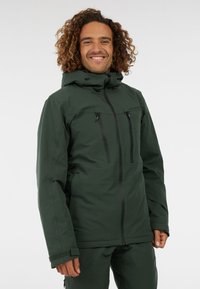 Groene waterdichte jas met een ritssluiting aan de voorkant, twee borstzakken, een verstelbare capuchon en geborduurde manchetten. Glad stof met zwarte accenten.