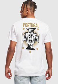 Hvid t-shirt med et stort grafisk design på bagsiden, hvor "Portugal" står over et skjolddesign, og tallene "2024" er i sort og guld accenter.