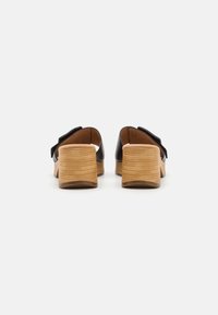 Svarta klacksandaler med en träblockklack. Öppen baksidesdesign och bred framrem. Slät läderöverkänsla med en matt finish.