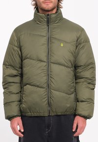 Olijfgroene pufferjack met een hoge kraag, ritssluiting aan de voorkant, een gestikte patroon en een klein logo op de linkerborst. Zacht, geïsoleerd materiaal.