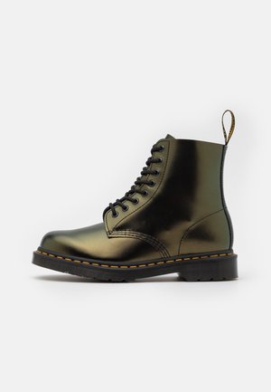 Black leather lace-up combat boot with yellow stitching and a branded pull tab on the heel, shown against a white background.