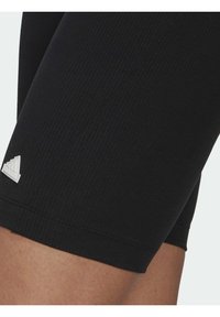 Svarta ribbade träningsshorts med en figurnära design, med en subtil vit logotyp på underbenet. Slät textur, längd till mitten av låret.