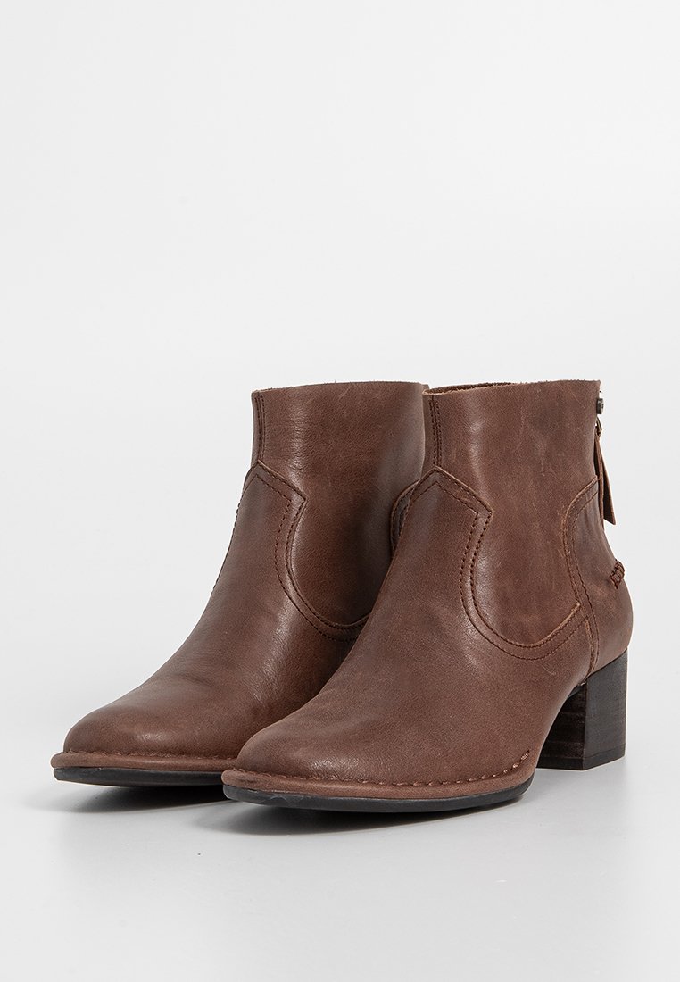 Paar braune Leder-Ankle-Boots mit Steppdetails und niedrigen Blockabsätzen, auf einem weißen Hintergrund präsentiert.