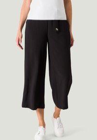 Zwarte culottebroeken van een zachte, vloeiende stof, met een drawstring tailleband met decoratieve zilveren uiteinden en brede, korte pijpen.