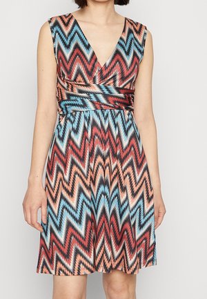 Sleeveless dress with deep V-neck and zigzag pattern in red, blue, black, and beige worn by a standing person.