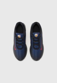 Tumši zili sporta apavi ar teksturētu tīkla augšdaļu, melniem akcentiem un sarkanu Nike zīmolu. Saišķēšanas dizains ar mīkstinātu zoli.