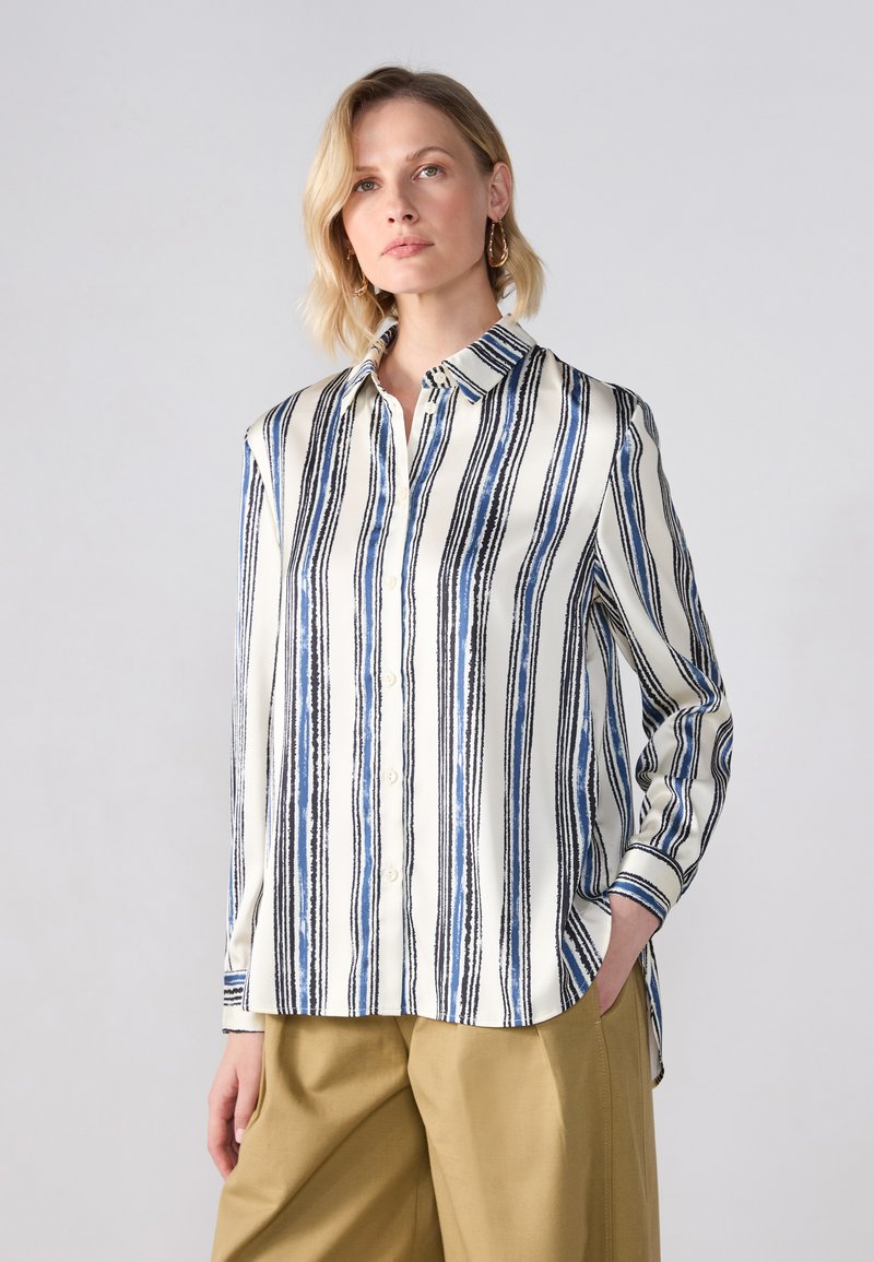 Blusa bianca con righe verticali blu e nere, design con bottoni e colletto classico. Presenta maniche lunghe e una vestibilità comoda.