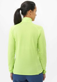 Pull vert à manches longues avec un motif en grille texturé, col montant et design ajusté, présenté de dos sur un fond clair.