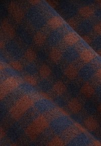 Tkanina w kratę w ciemnoniebieskim i rdzawym kolorze. Tekstura wydaje się miękka i lekko puszysta, z wyraźnym wzorem w kratkę.