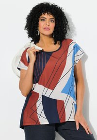 Top multicolor con formas geométricas en azul, rojo y crema con líneas sutiles. Mangas cortas, escote redondo, tejido ligero.