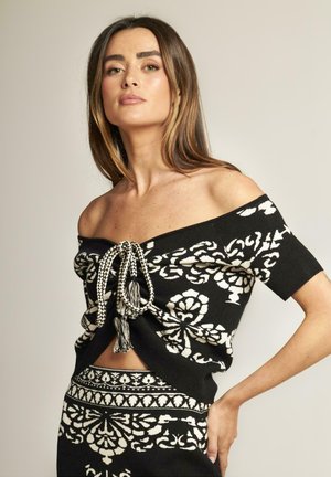 Top lavorato a maglia nero con motivi floreali bianchi, design senza spalline, chiusura anteriore con dettagli intrecciati e maniche corte.