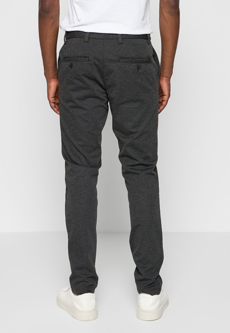 Ciemnoszare spodnie o slim fit, wykonane z miękkiego materiału. Zawierają dwie tylne kieszenie i są noszone z białymi sneakersami.