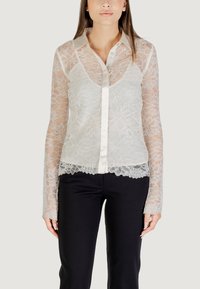 Blusa di pizzo con maniche lunghe in tulle, motivo floreale e collo in satin. Presenta una chiusura a bottoni e un orlo con pizzo scallop.