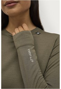 Olijfgroen langarmshirt met een ronde halslijn en een gestructureerde stof. Heeft geborduurde tekst op de mouw en een logo-opdruk nabij de kraag.