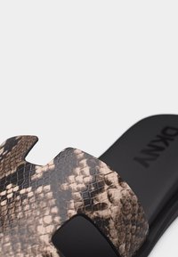 Sandale à glissière avec semelle noire et bride en motif peau de serpent marron, dotée d'une finition texturée et d'un design découpé.