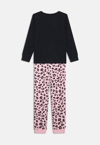 Svart långärmad tröja i kombination med rosa byxor med svart leopardmönster. Båda är i mjukt tyg med ribbade mudd.