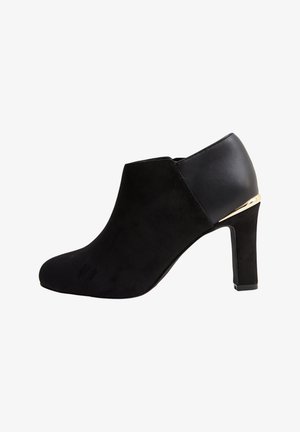 Bottines noires avec un dessus en daim, au design épuré, bout effilé et un talon haut avec un dos accentué en or.