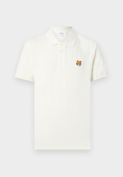 Polo blanc à manches courtes avec trois boutons et petite tête de renard orange brodée sur le côté gauche de la poitrine.