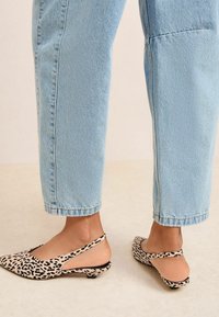Sandalete cu imprimeu de leopard, cu toc jos, fabricate dintr-un material moale. Botul ascuțit și părțile laterale decupate adaugă detalii de design unice. Purtați cu blugi decolorati.