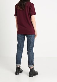 Bordeaux kortärmad t-shirt matchad med uppvikt ljusblå jeans och svarta ankelkängor, med en enkel och ren design.