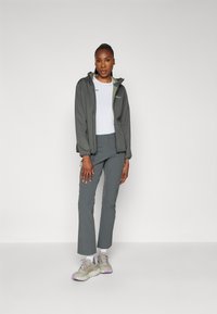 Grijze zip-up jas met capuchon, witte shirt, grijze broek en lichtgrijze sneakers met paarse accenten, met een relaxte fit en zachte textuur.