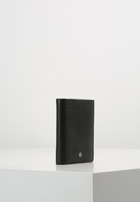 Portafoglio in pelle nera con finitura testurizzata, design compatto, caratterizzato da un piccolo accento metallico sulla parte anteriore. Forma semplice e minimalista.