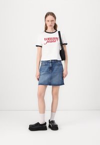 Fehér póló piros "tommy jeans" logóval, kék farmer szoknyával, fekete vastag talpú cipőkkel és fehér zoknikkal. Egyszerű dizájn kontrasztos színekkel.