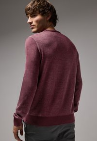 Burgundský svetr s dlouhými rukávy, strukturovanou tkaninou, pletenými manžetami a lemem, kulatým výstřihem a mírně přiléhavým střihem.