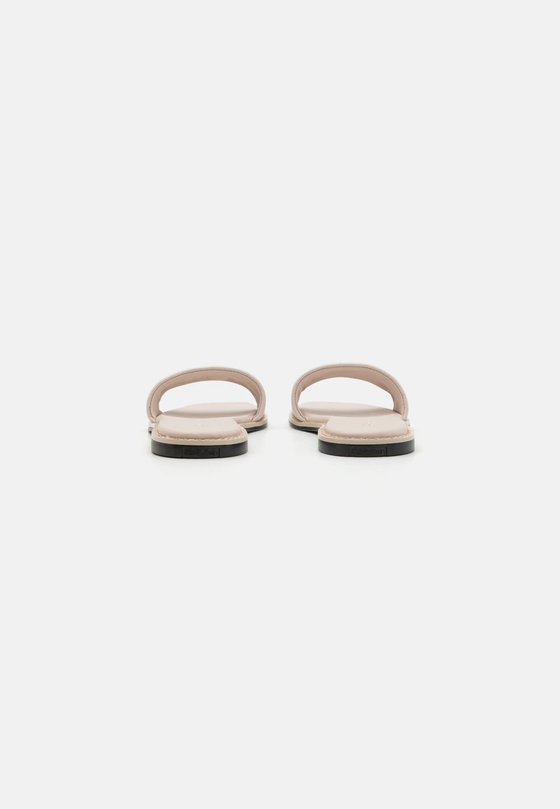 Sandales à enfiler avec une tige en cuir rose clair doux, semelle noire plate et un design minimaliste comprenant deux fines brides sur le cou-de-pied.