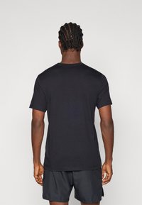 Μαύρο βαμβακερό μπλουζάκι με κοντά μανίκια, στρογγυλή λαιμόκοψη και άνετη εφαρμογή. Λείος υφασμάτινος χαρακτήρας χωρίς ορατά λογότυπα ή σχέδια.