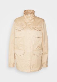 Beige nylon outerwear jacket with a high collar, long sleeves, and four front pockets. Features elastic cuffs and a subtle Nike logo.