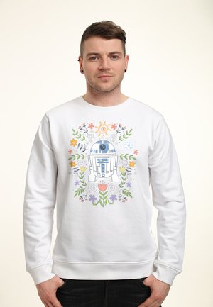 Man wearing white sweatshirt with colorful floral design surrounding blue and white R2-D2 robot illustration.
